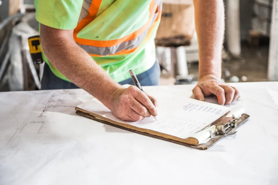 Site supervisor filling in a checklist on a clipboard